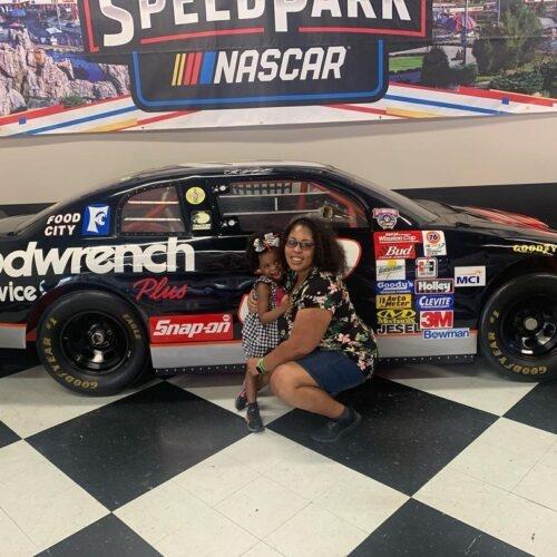 A mom and daughter posing in front of a NASCAR